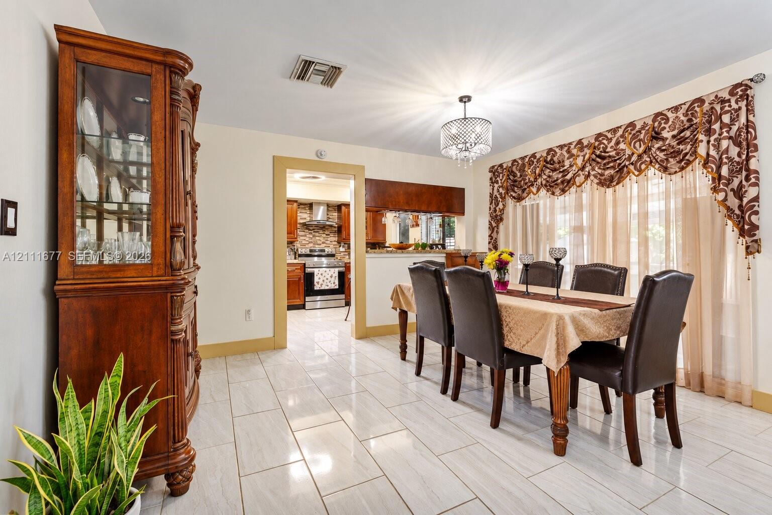 Dining area featuring neutral tile flooring, a crystal-accented chandelier, and expansive windows