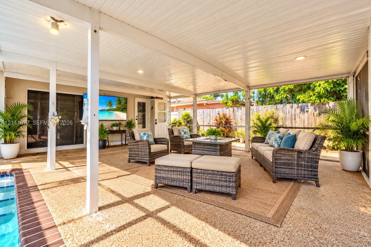 Screened-in covered patio featuring a textured aggregate floor, recessed lighting, and sliding glass door access