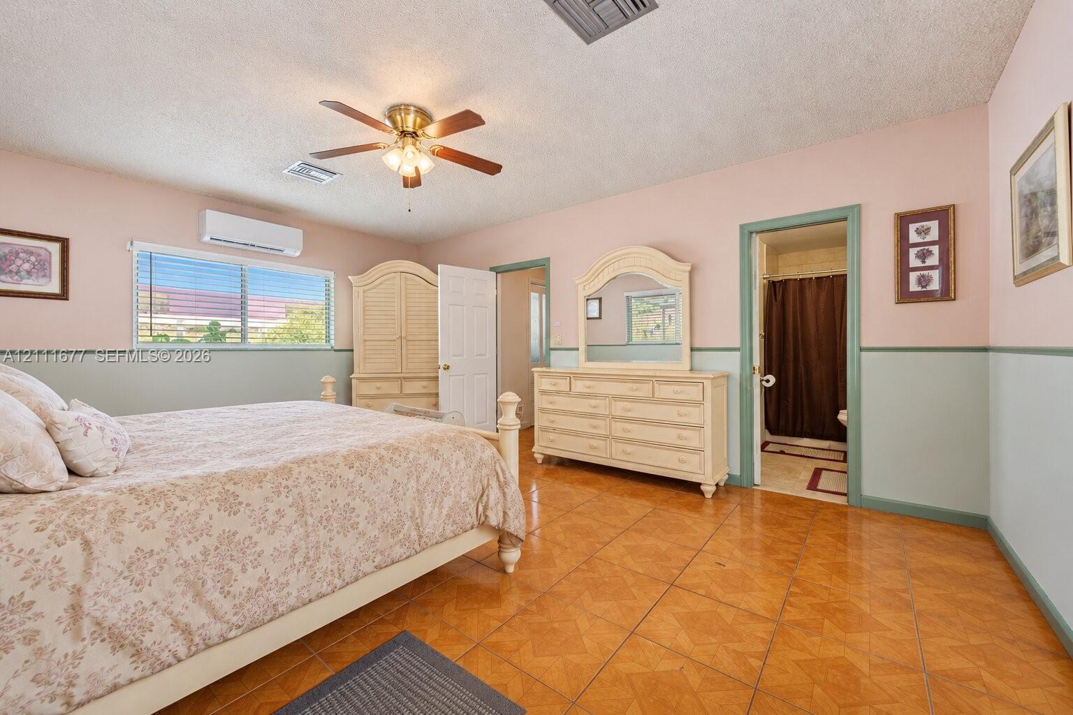 Room featuring ceramic tile flooring, a wall-mounted mini-split HVAC unit, and a ceiling fan with integrated lighting