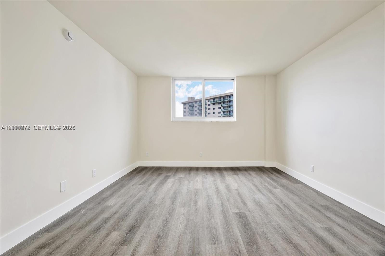 Interior space featuring neutral-toned walls, wood-finish flooring, and a sliding window