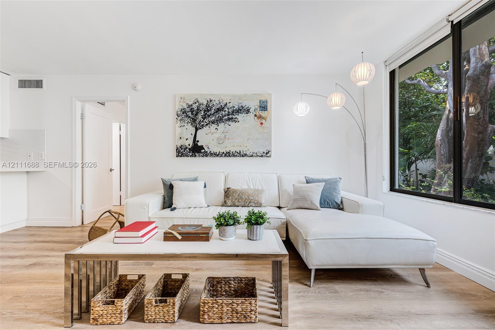 Living area featuring wood-finish flooring, floor-to-ceiling windows, and white walls