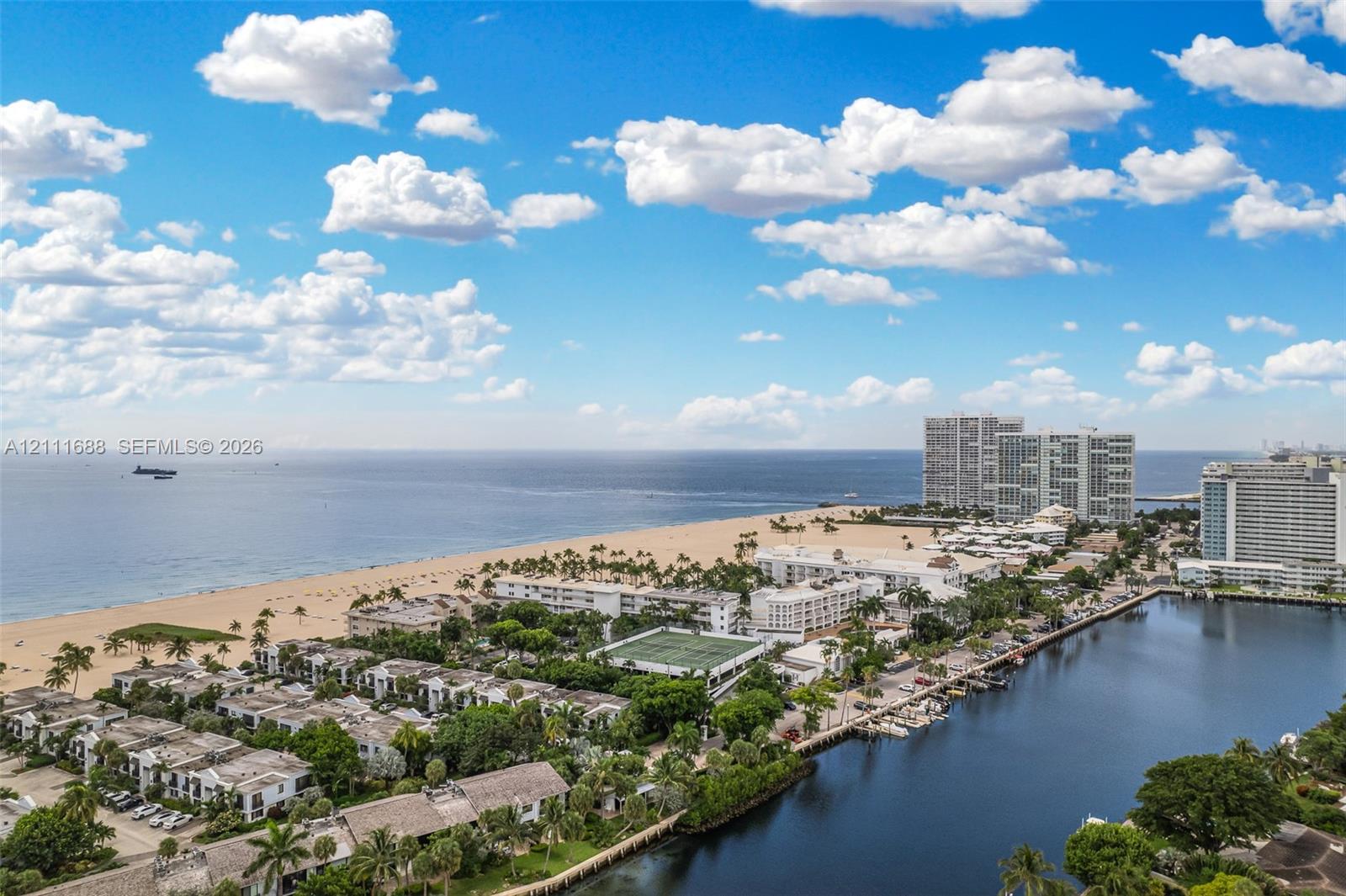Aerial perspective featuring coastal shoreline, sandy beach, waterway, and tennis court