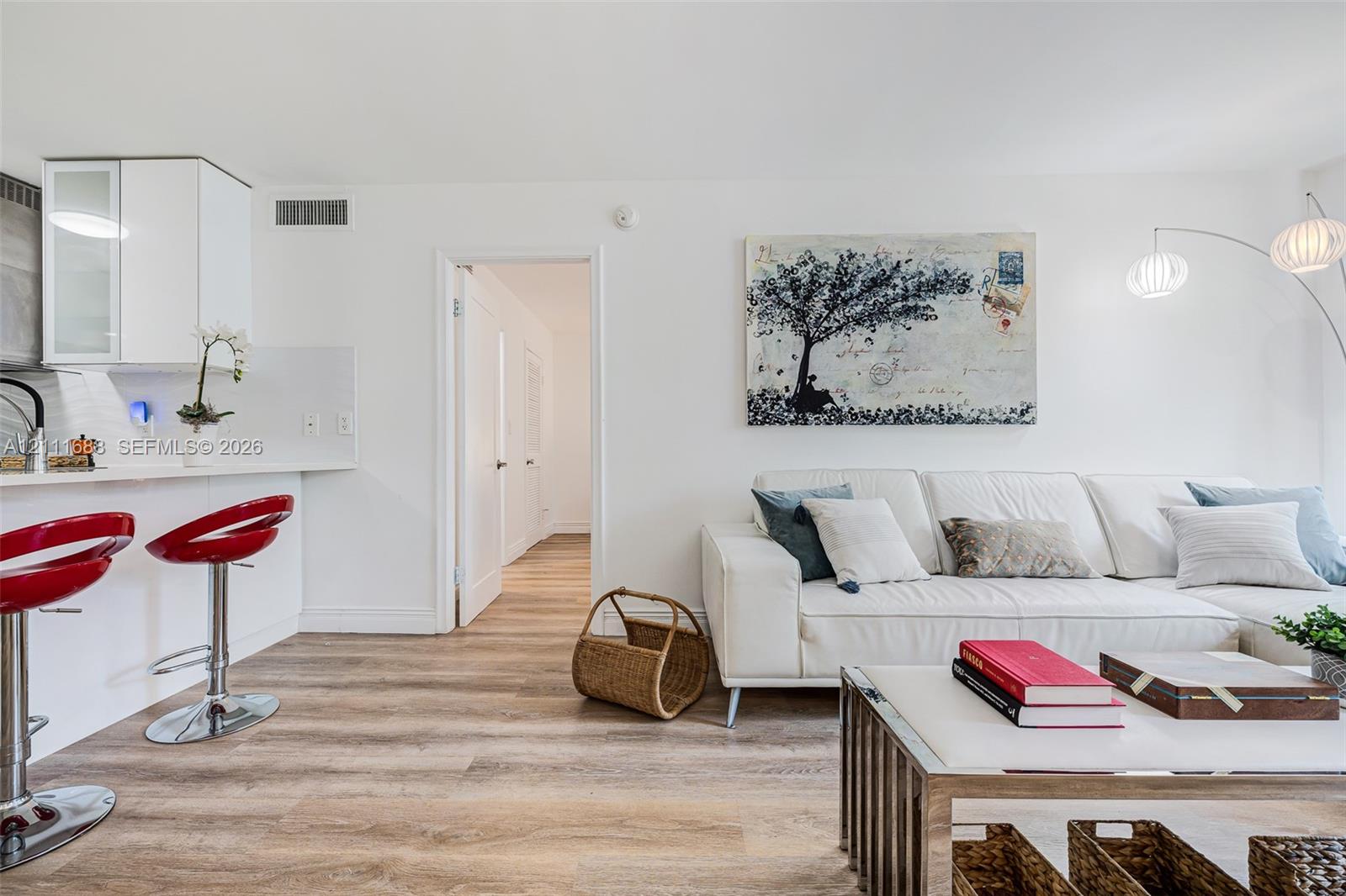 Open-concept floor plan featuring wood-finish flooring, white flat-panel cabinetry, and a peninsula counter