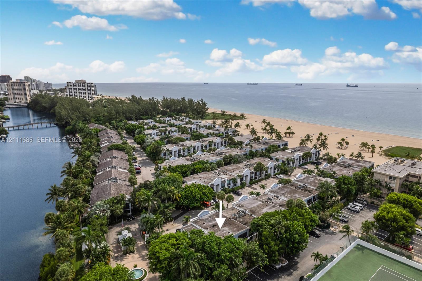Aerial perspective of coastal property featuring proximity to the ocean, sandy beachfront, and a canal