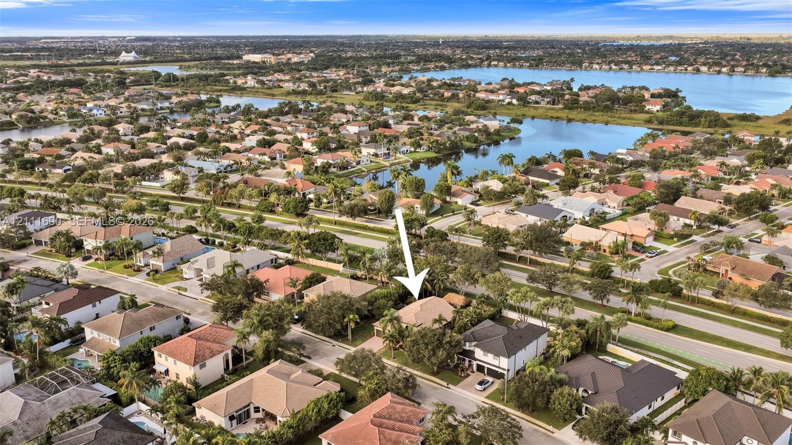 Aerial perspective of a residential property featuring a tiled roof, multi-car garage, and mature landscaping within a suburban community