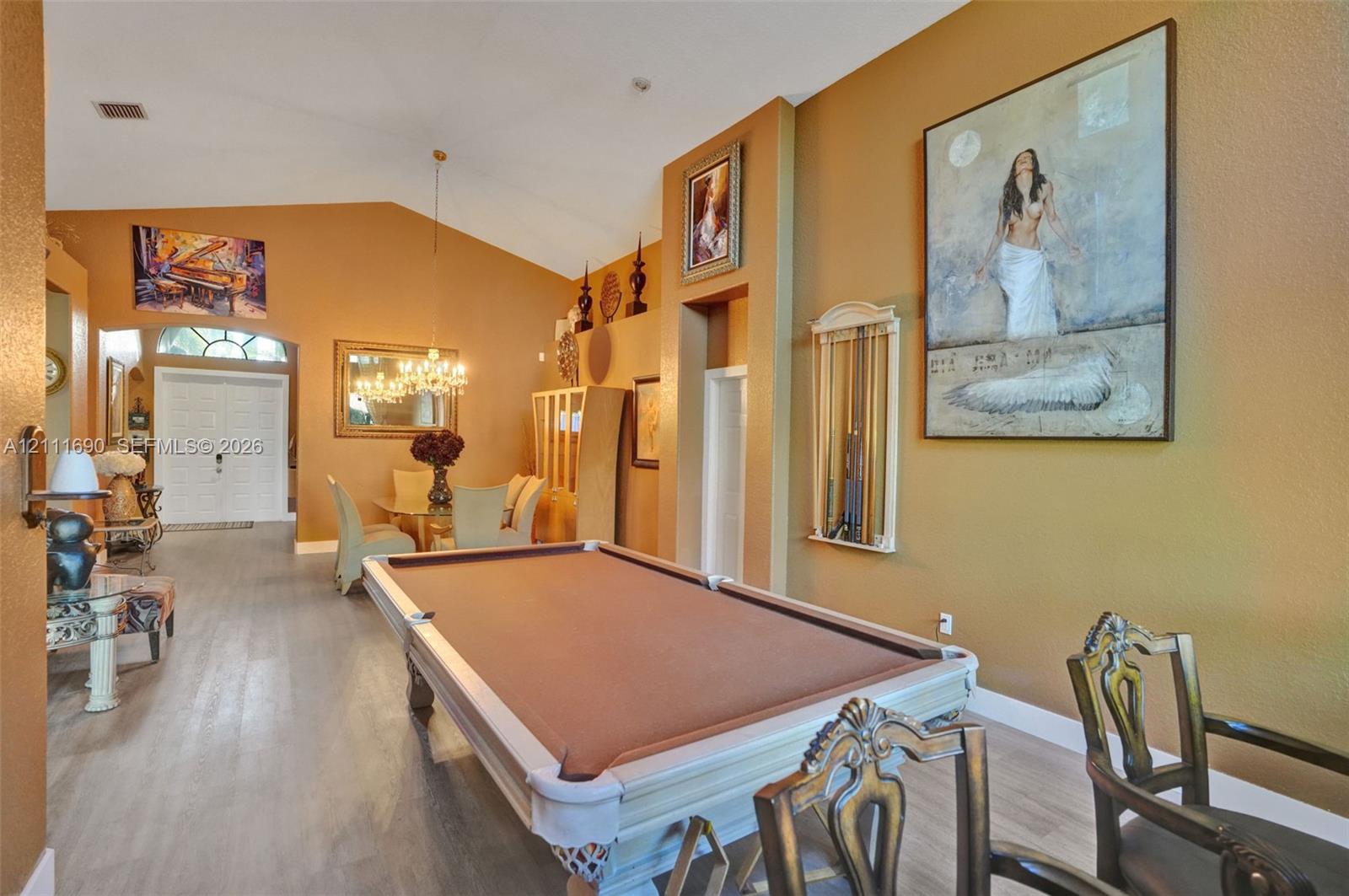 Vaulted ceilings, wood-finish flooring, architectural wall niches, crystal chandelier, and arched transom window entry