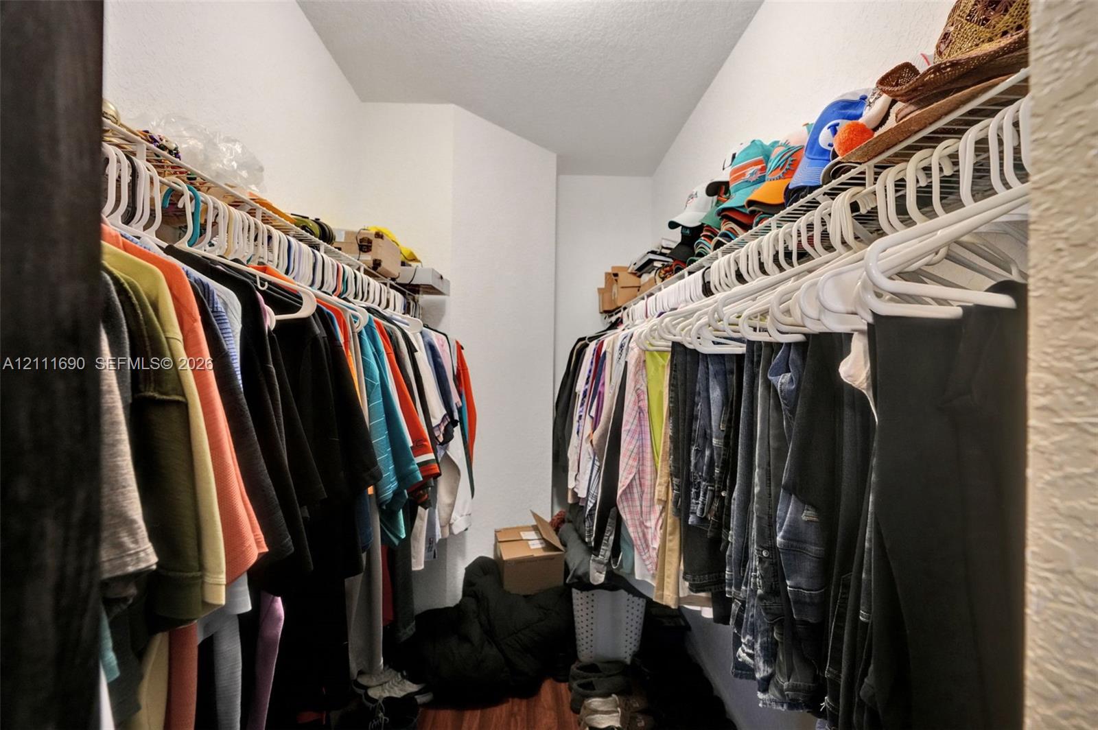 Walk-in closet featuring dual levels of white wire shelving and wood-finish flooring