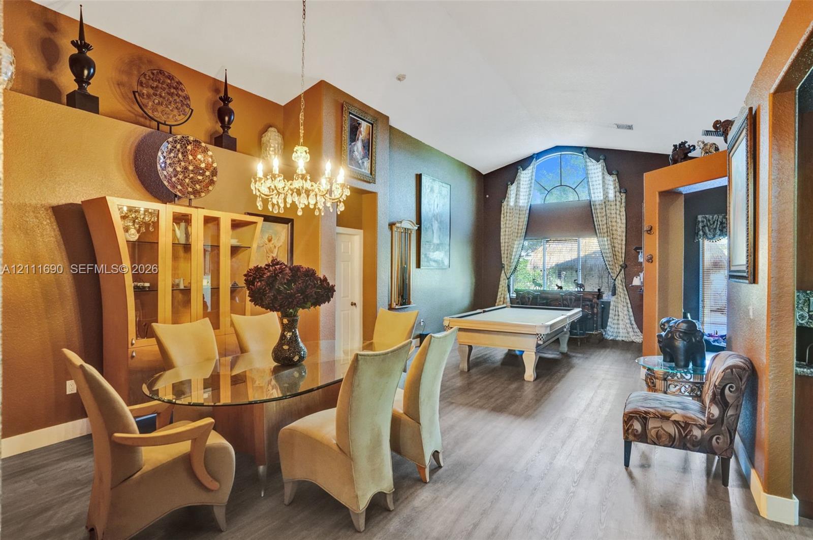Vaulted ceilings, wood-finish flooring, built-in recessed display niches, an ornate crystal chandelier, and a large arched window