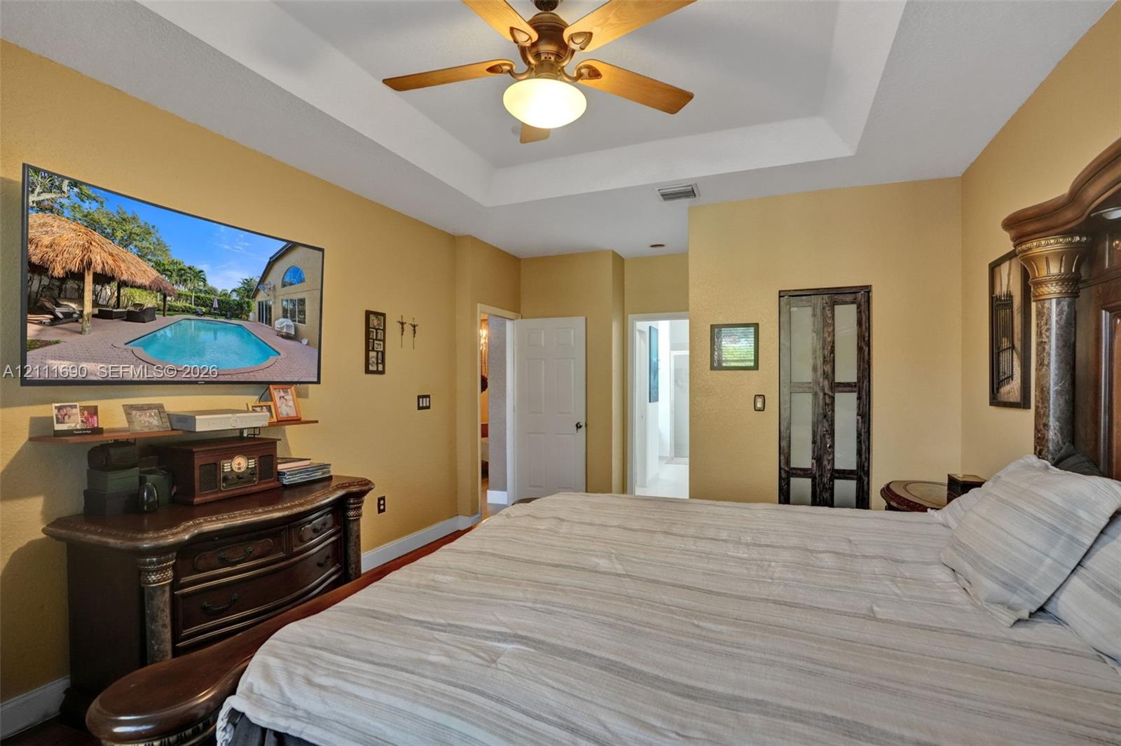Tray ceiling featuring a central multi-blade ceiling fan with integrated lighting