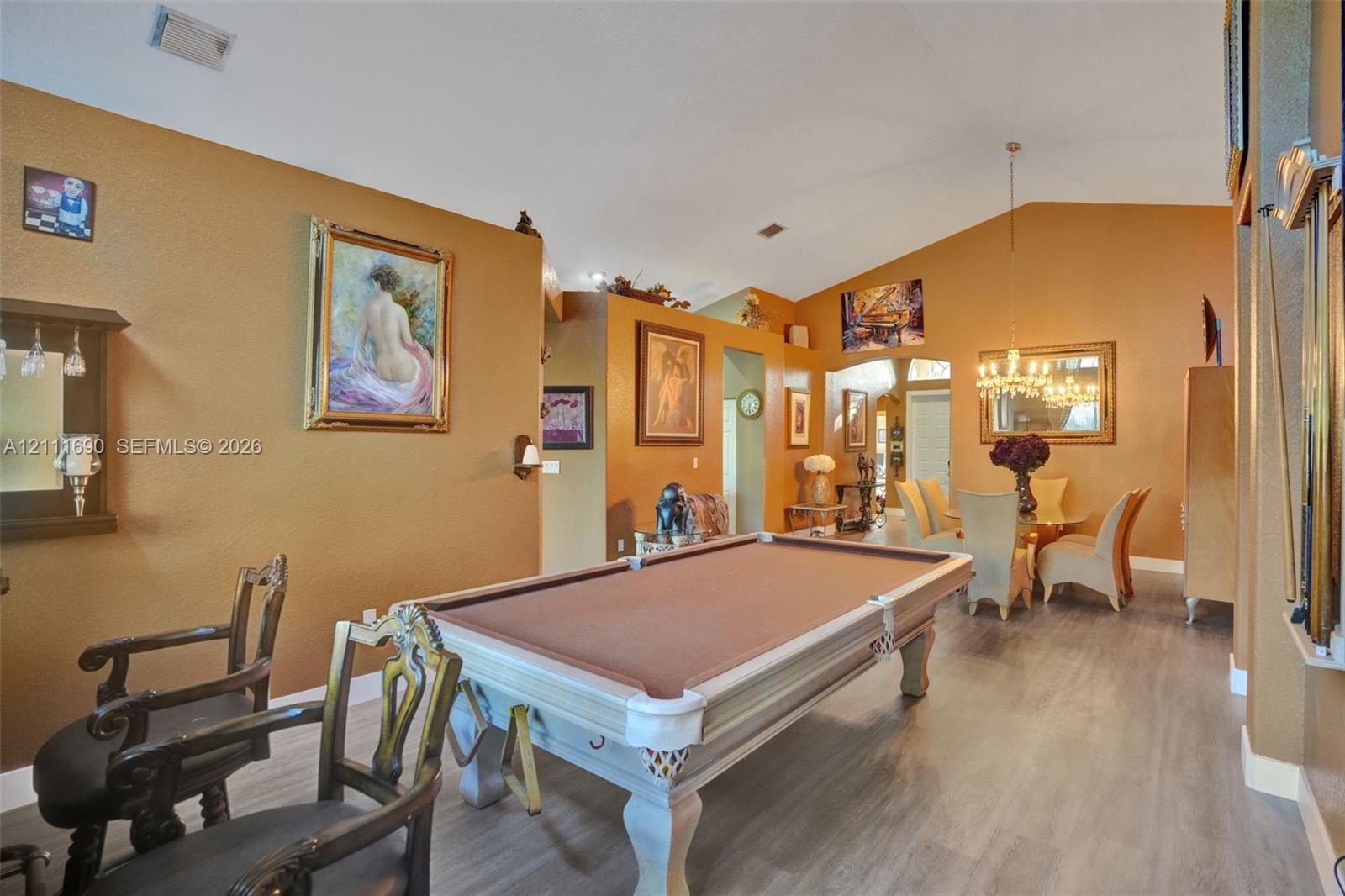 Vaulted ceilings, wood-finish flooring, and a multi-arm chandelier