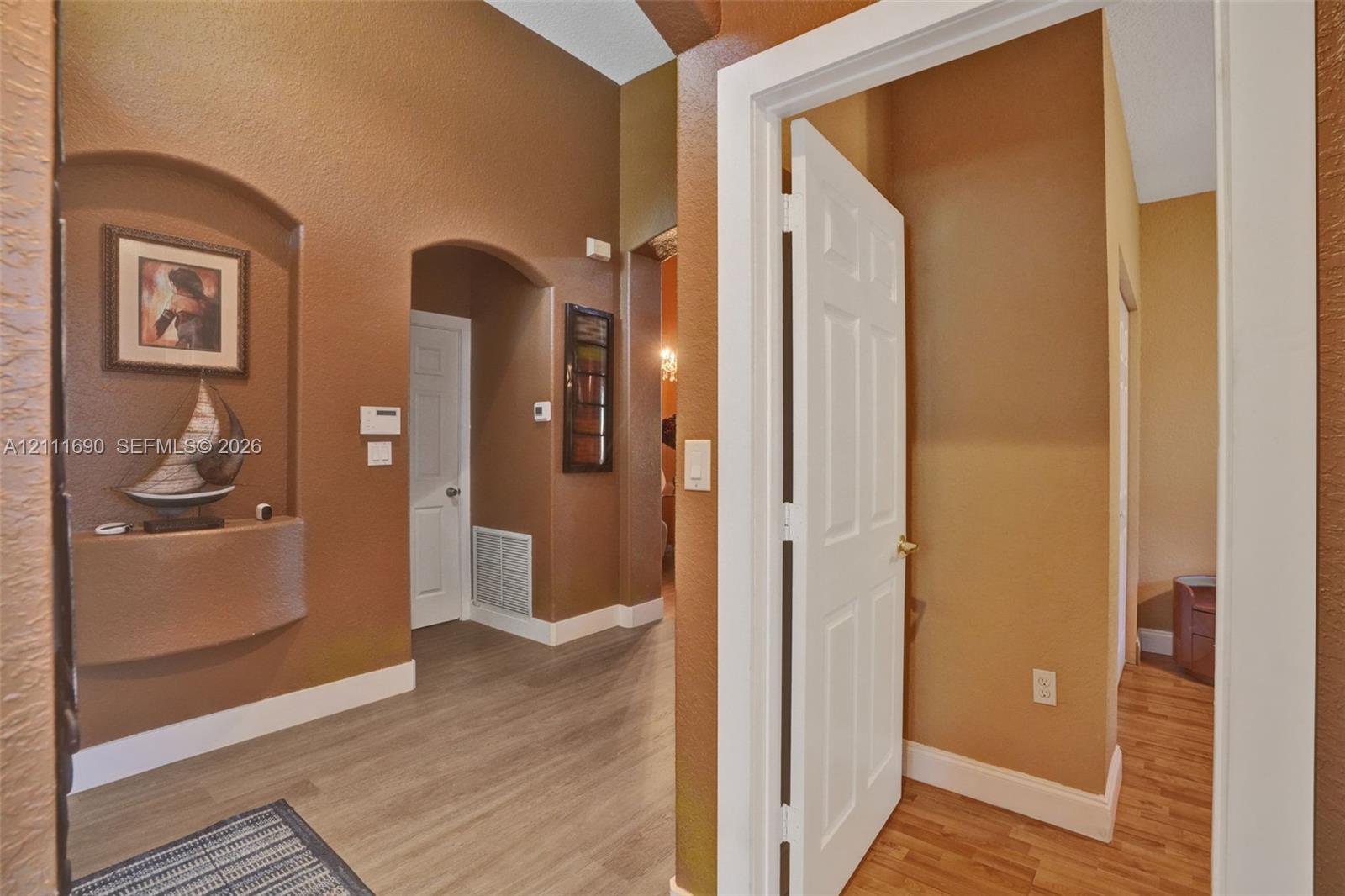 Entryway featuring vaulted ceilings, arched wall niches, multi-panel doors, and wood-finish flooring