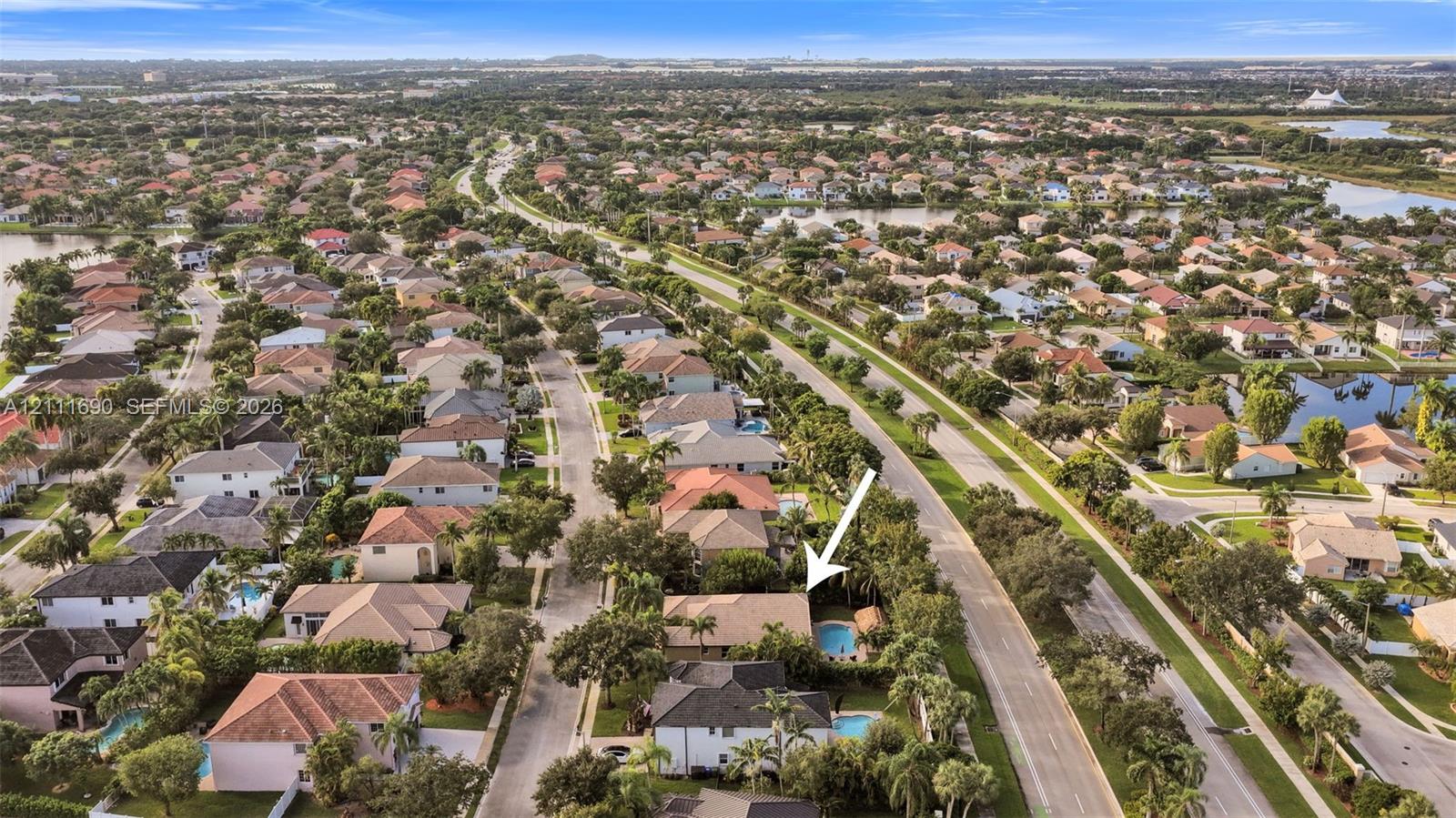 Aerial perspective of a single-family residence featuring a private swimming pool, concrete tile roof, and mature perimeter landscaping