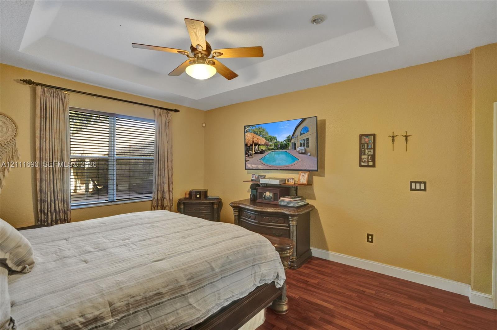 Tray ceiling, wood-finish flooring, and ceiling fan with integrated lighting