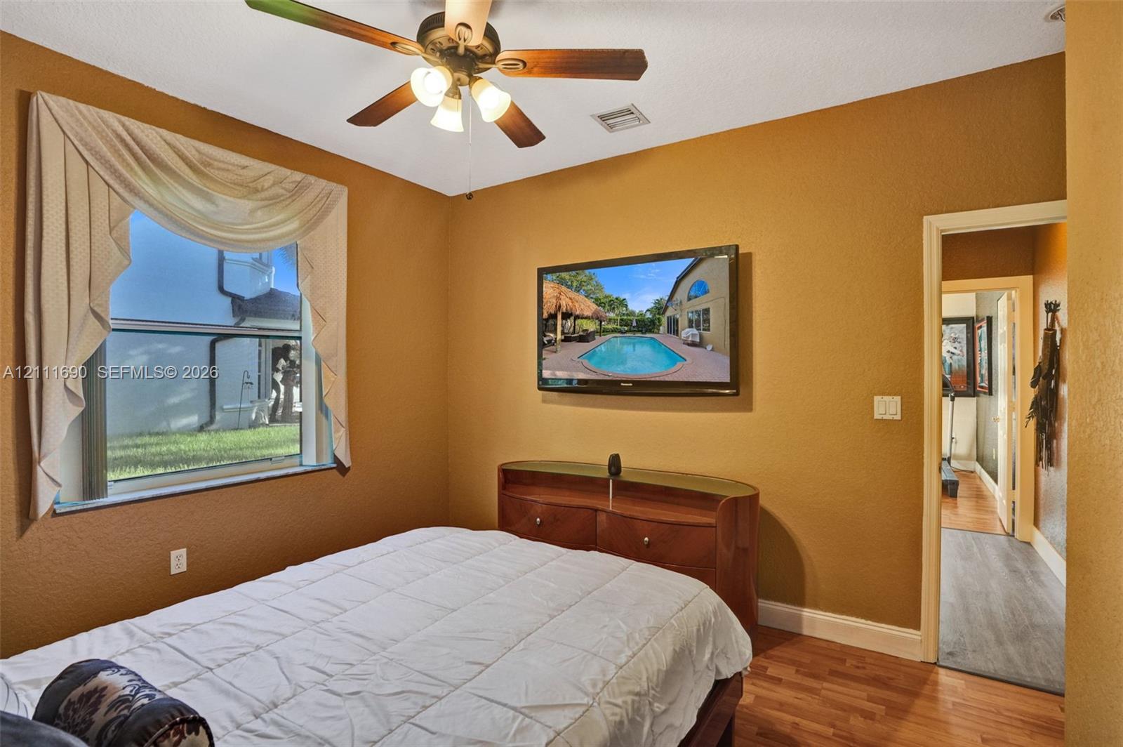 Room featuring wood-finish flooring, a multi-blade ceiling fan with integrated lighting, and a single-hung window