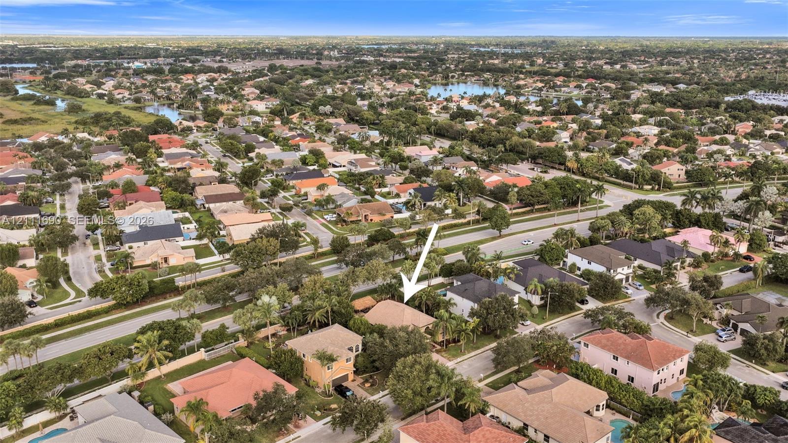 Aerial perspective of a single-story residence featuring a hipped roofline, mature landscaping, and an attached multi-car garage