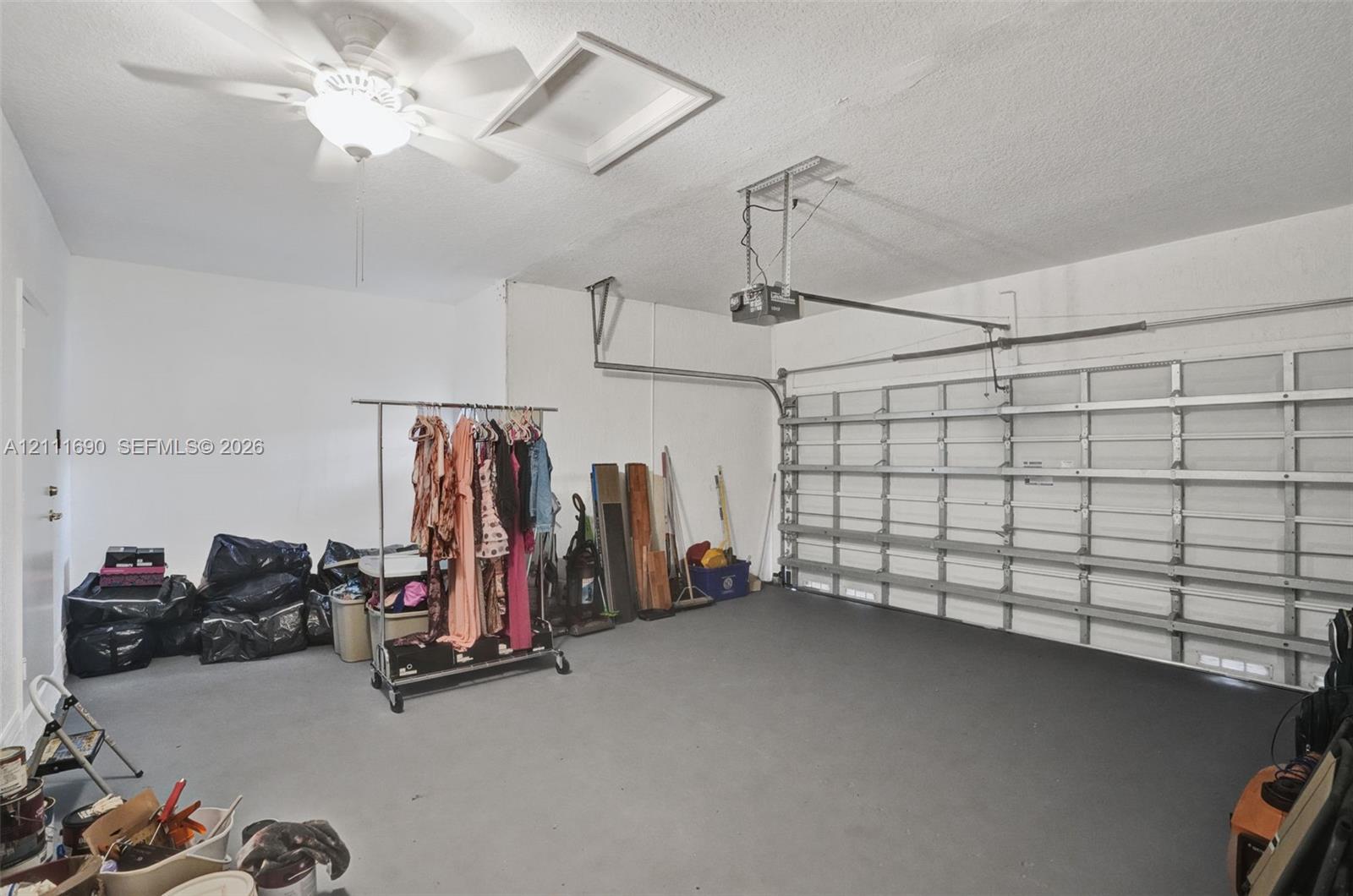 Garage interior featuring painted concrete flooring, an overhead automatic door opener, and a ceiling-mounted light fixture