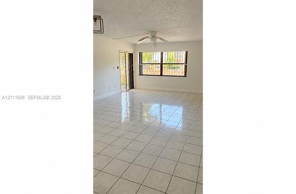 Open living space featuring tile flooring, ceiling fan, and window security bars