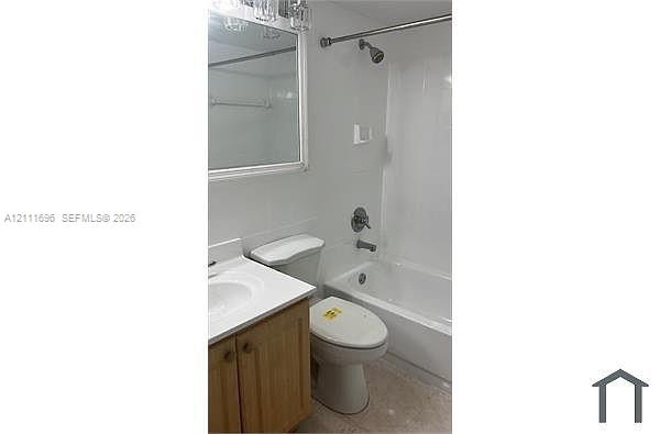 Bathroom featuring wood-finish cabinetry, white countertop with integrated sink, wall-mounted mirror, and tub-shower combination with chrome fixtures