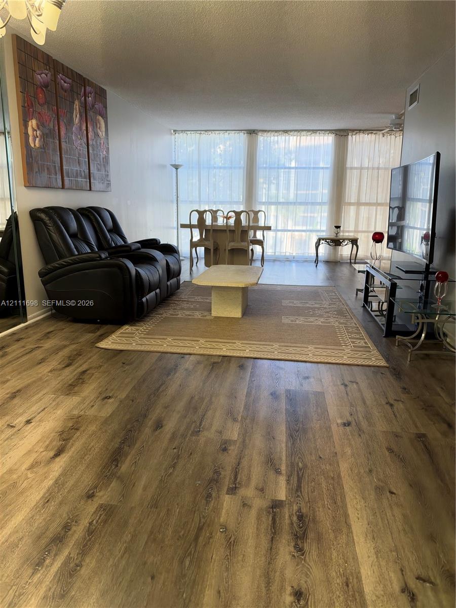 Living area featuring wood-finish flooring, floor-to-ceiling windows, and a mirrored closet wall
