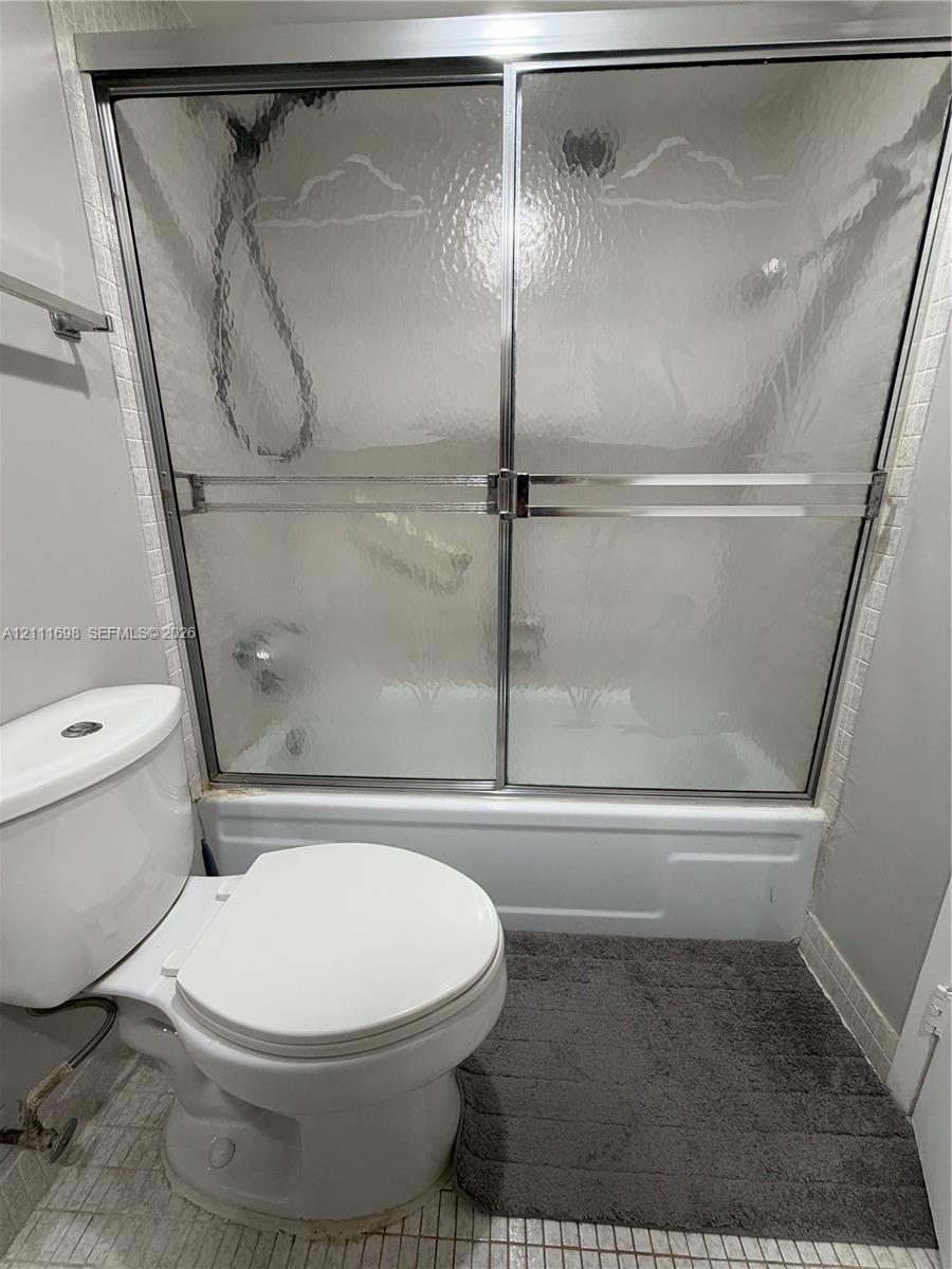 Bathtub and shower combination featuring a chrome-framed sliding glass enclosure, white porcelain-finish basin, and chrome hardware