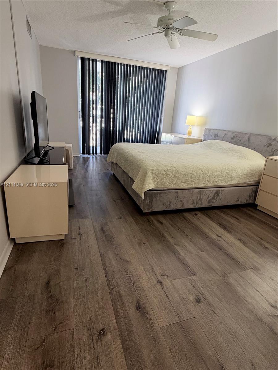 Wood-finish flooring, ceiling fan with integrated lighting, and full-length vertical window blinds