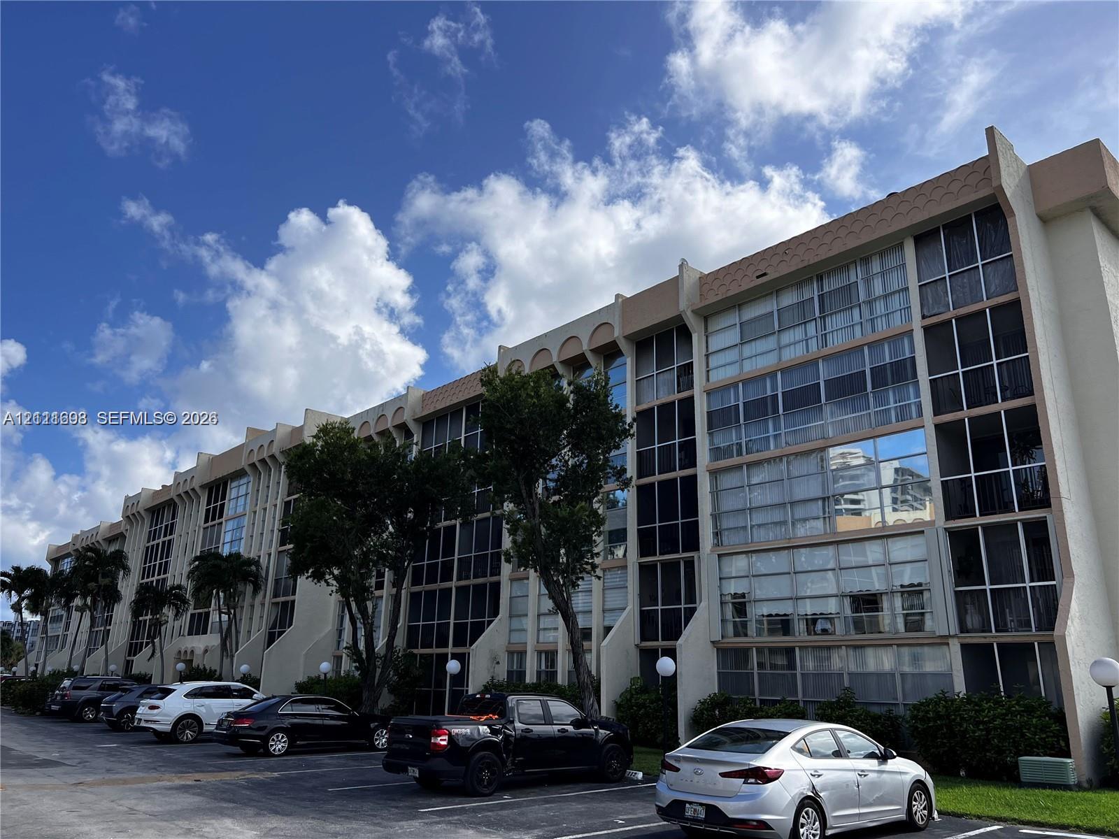 Mid-rise multi-story building featuring structural concrete columns, expansive glass windows with black framing, and decorative scalloped roofline details Mid-rise multi-story building featuring structural concrete columns, expansive glass windows with black framing, and decorative scalloped roofline details