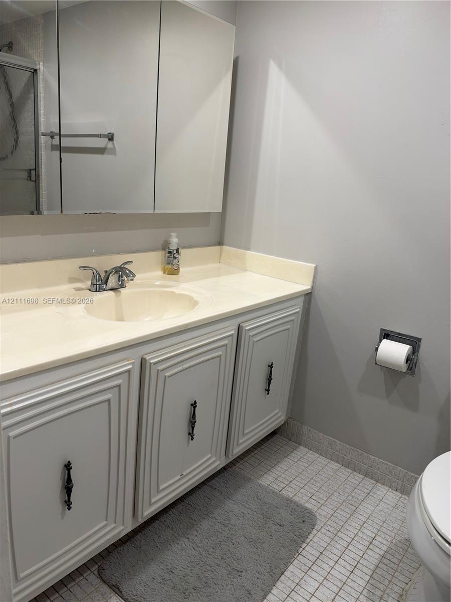 Bathroom vanity featuring painted cabinetry, a neutral integrated countertop with an oval basin, a chrome dual-handle faucet, and a wall-mounted mirrored medicine cabinet