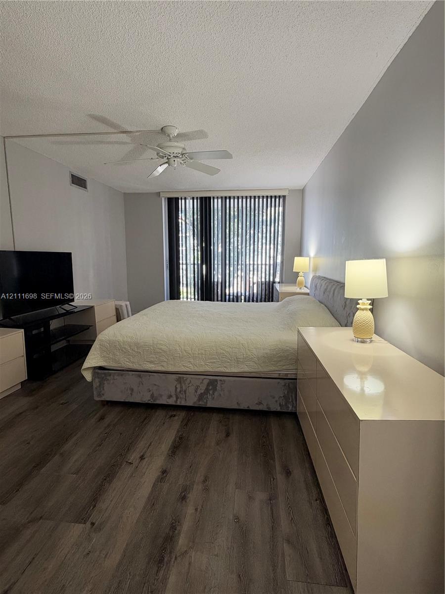 Wood-finish flooring, neutral wall tones, ceiling fan, and vertical blinds
