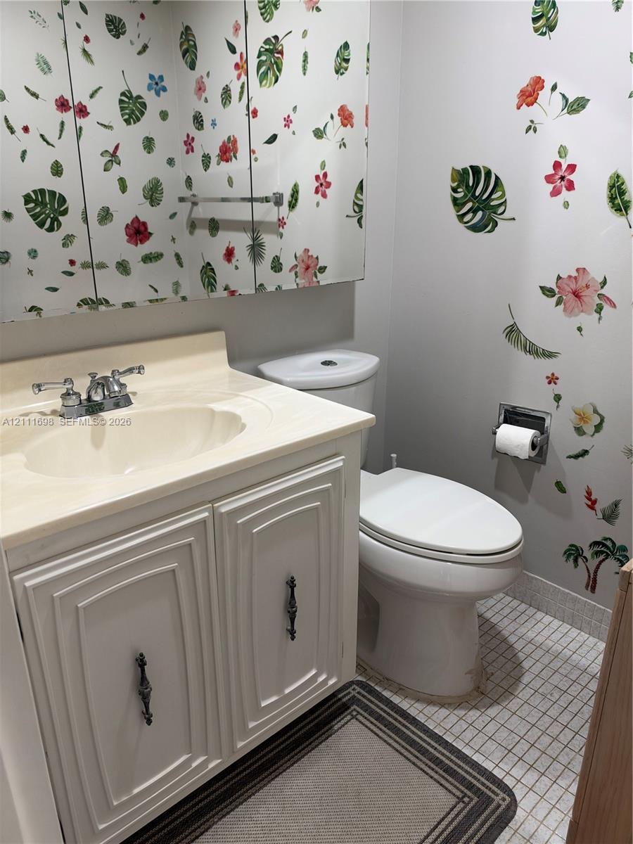 Bathroom featuring a vanity with integrated sink, chrome dual-handle faucet, mirrored medicine cabinet, and tiled flooring
