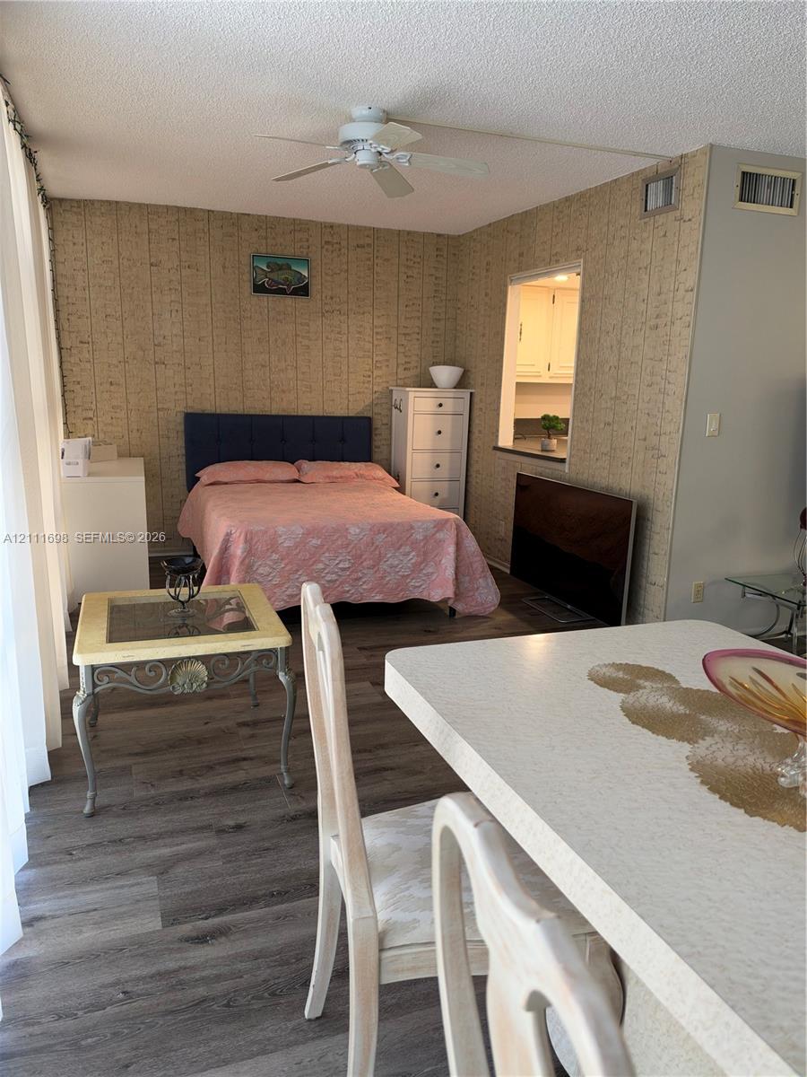 Wood-finish flooring, textured wallpaper, ceiling fan, and pass-through opening