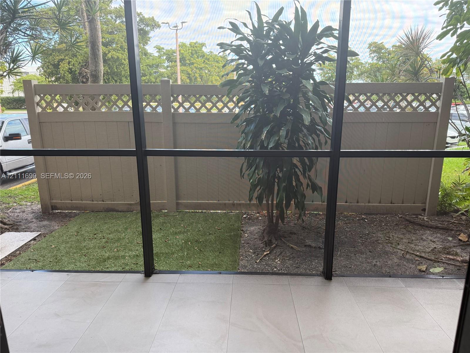 Screened patio featuring large format tile flooring and a vinyl privacy fence with lattice detailing
