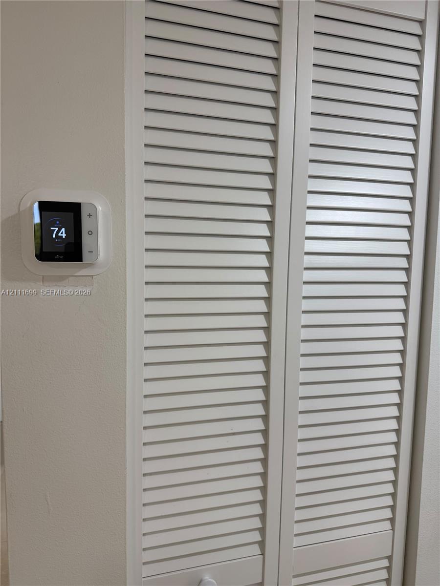 Digital smart thermostat and white bi-fold louvered closet doors