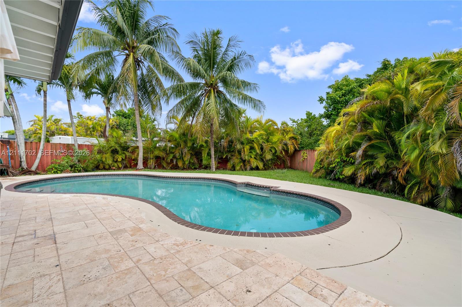 Freeform swimming pool with brick coping, tile patio, and established perimeter landscaping