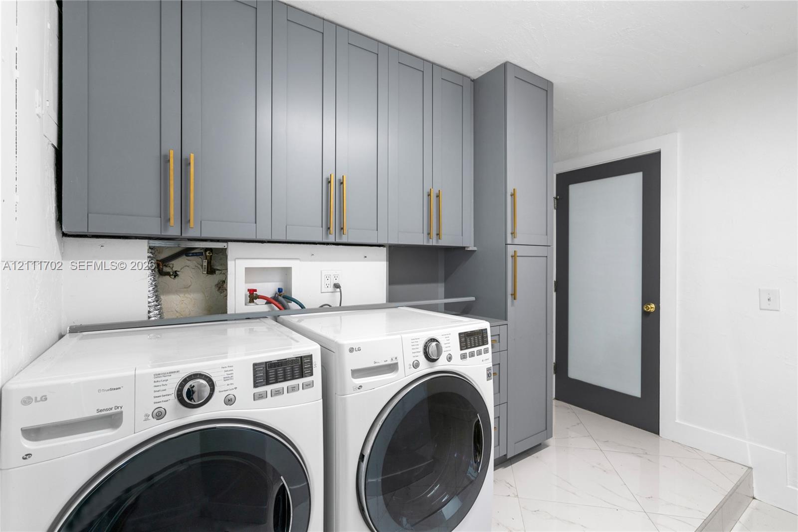 Shaker-style cabinetry in grey featuring vertical gold-tone hardware, full-length pantry cabinet, and a door with a frosted glass panel Shaker-style cabinetry in grey featuring vertical gold-tone hardware, full-length pantry cabinet, and a door with a frosted glass panel