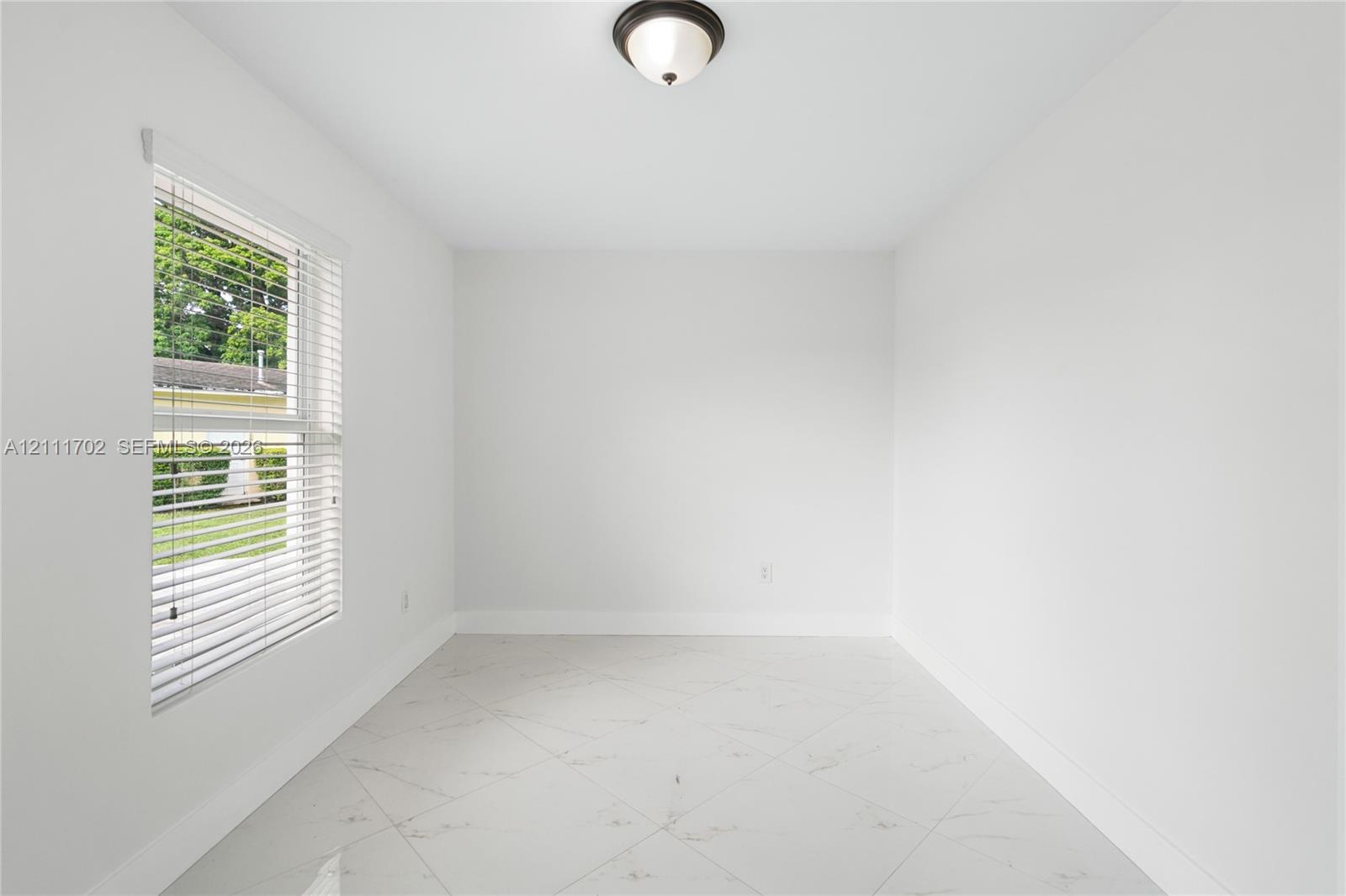 Interior room featuring large-format diagonal tile flooring, a window with horizontal blinds, and a flush-mount ceiling light fixture