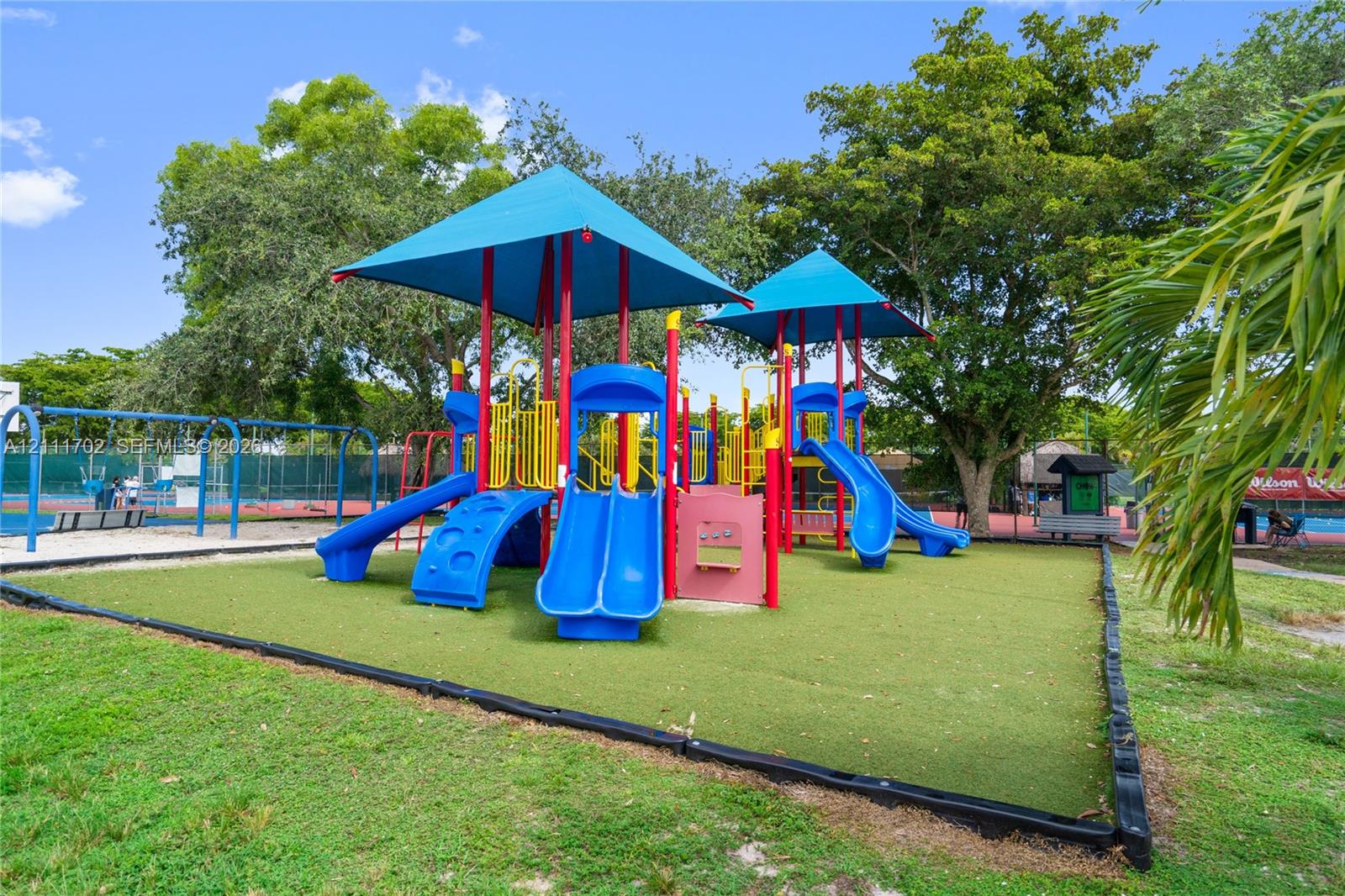 Playground featuring multi-level structures, shade canopies, integrated slides, and synthetic grass surfacing