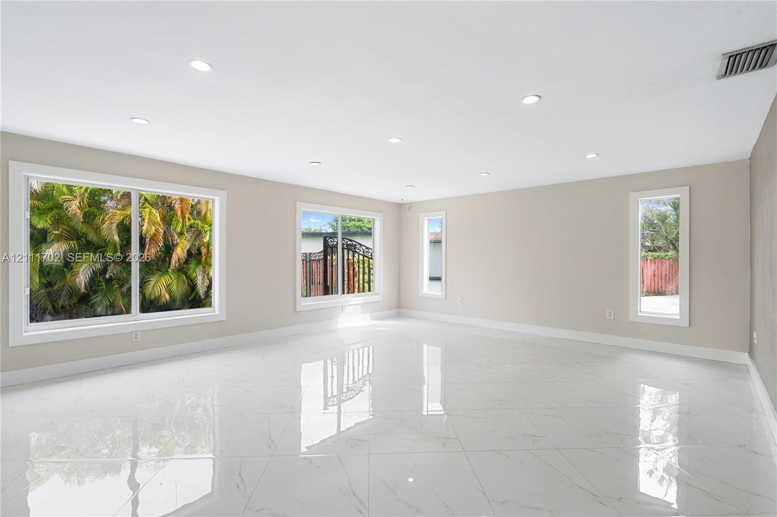 Neutral-toned interior featuring large-format polished tile flooring, recessed lighting, and multiple windows providing natural light Neutral-toned interior featuring large-format polished tile flooring, recessed lighting, and multiple windows providing natural light