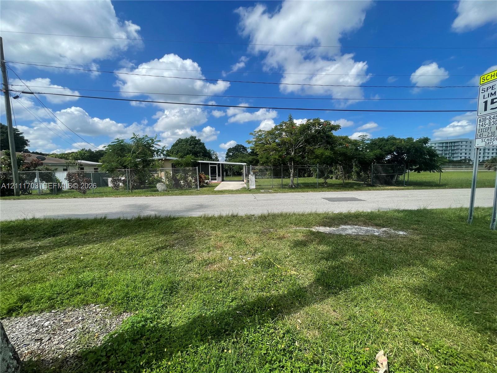 Single-story residence featuring a paved entryway, chain-link perimeter fencing, and mature trees Single-story residence featuring a paved entryway, chain-link perimeter fencing, and mature trees