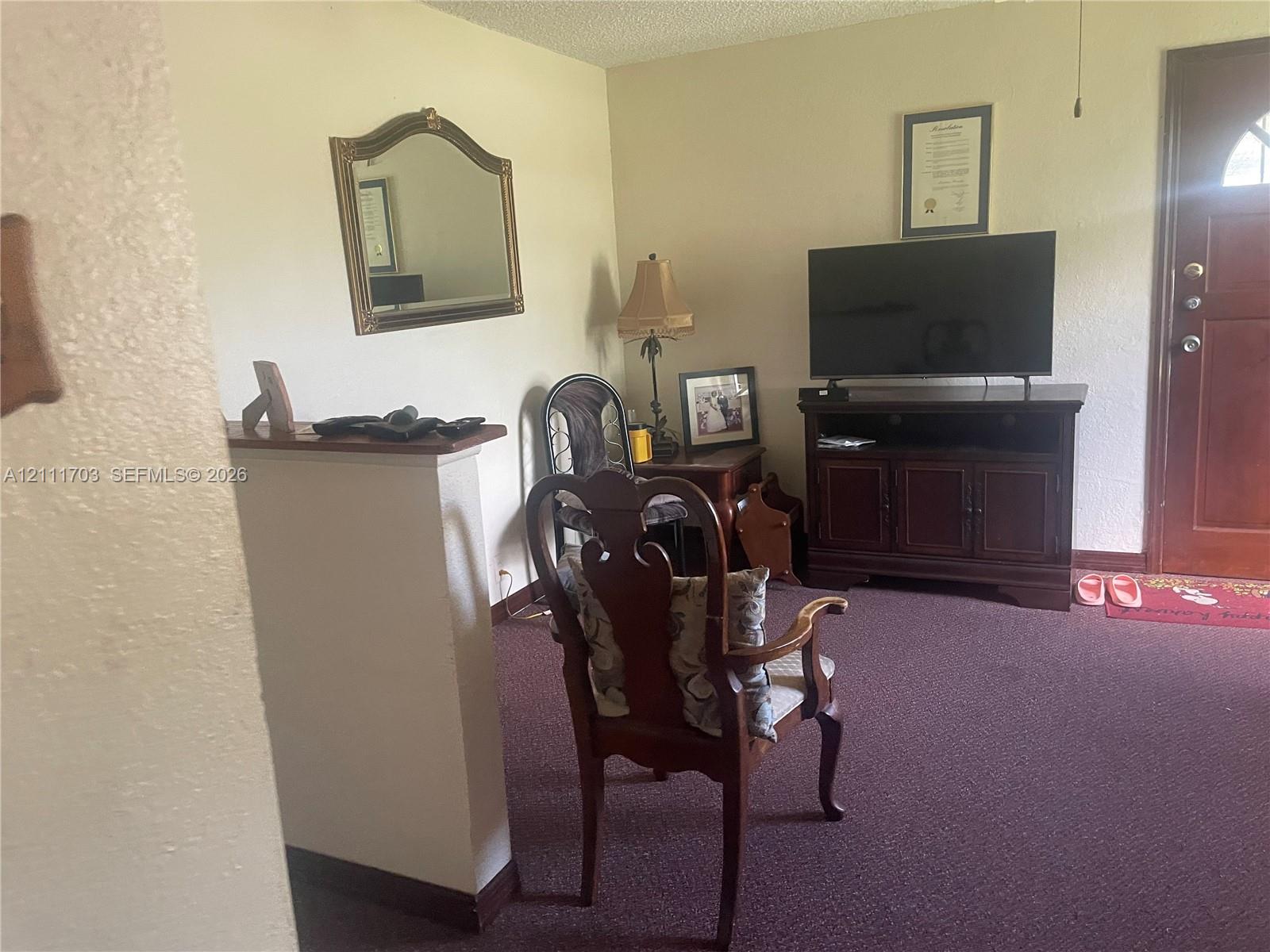 Half-wall room divider, carpeted flooring, and wood-paneled entry door with glass pane Half-wall room divider, carpeted flooring, and wood-paneled entry door with glass pane