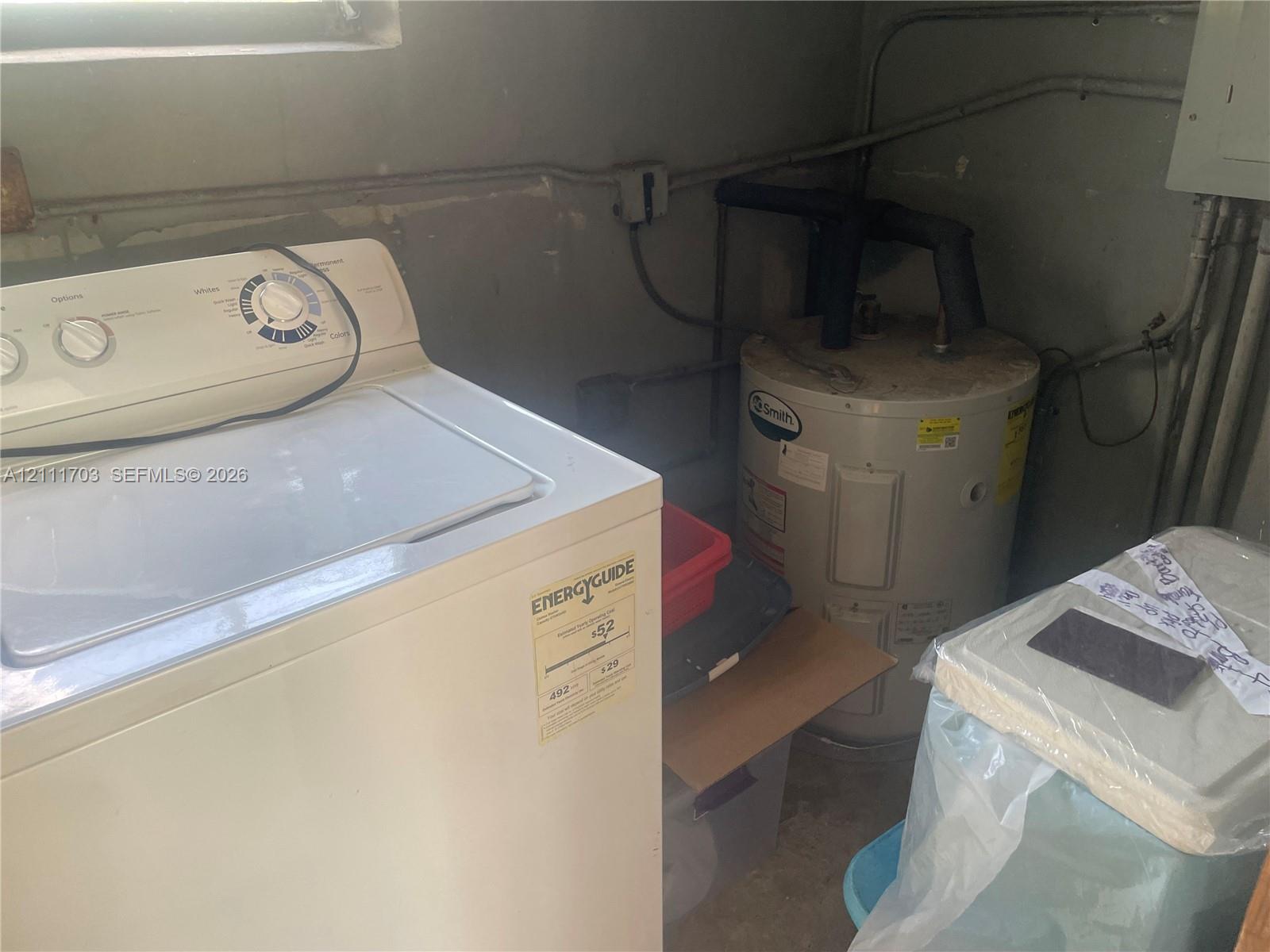 Utility area featuring a top-load washer and a vertical water heater