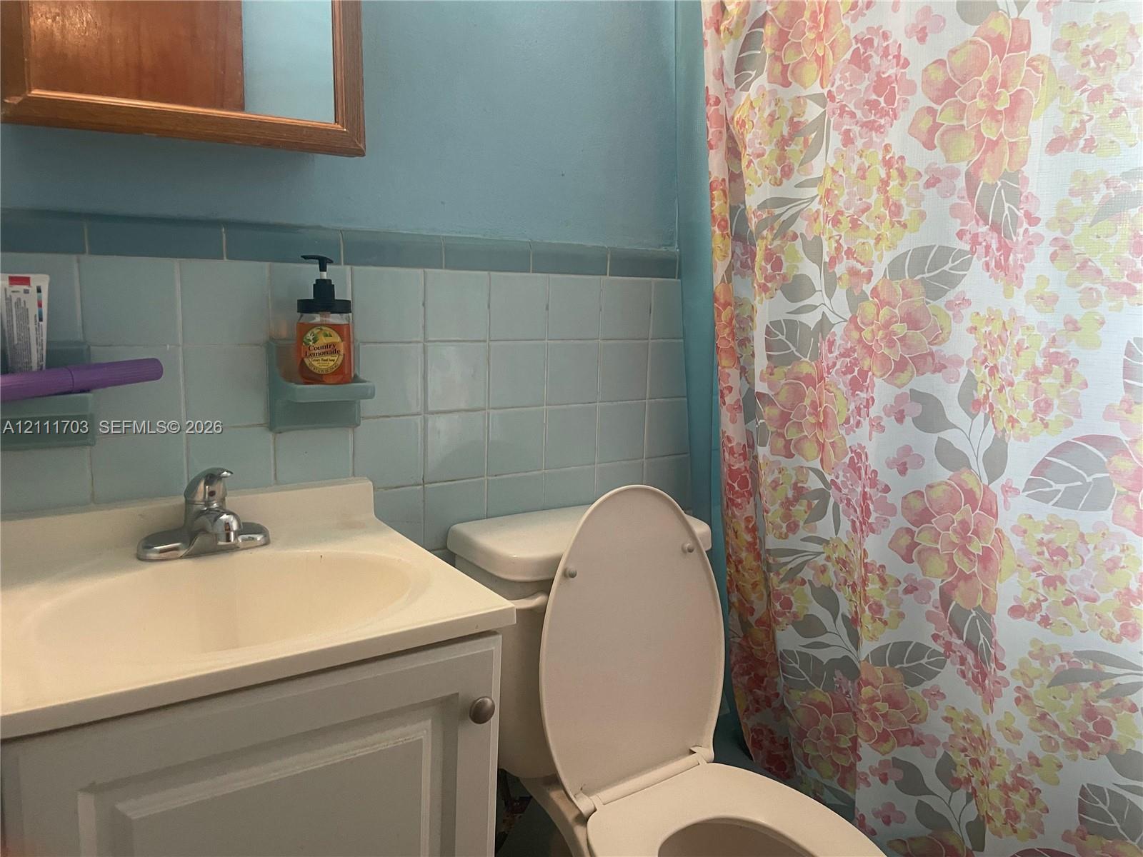Bathroom featuring a vanity with an integrated sink and chrome faucet, light blue ceramic wall tiling, and a built-in recessed soap dish
