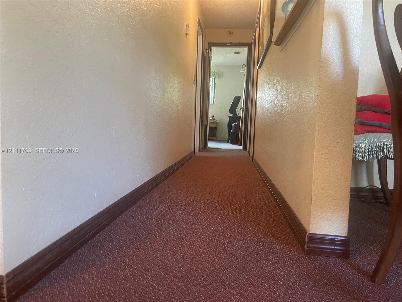 Hallway featuring wall-to-wall carpeting and wood-finish trim
