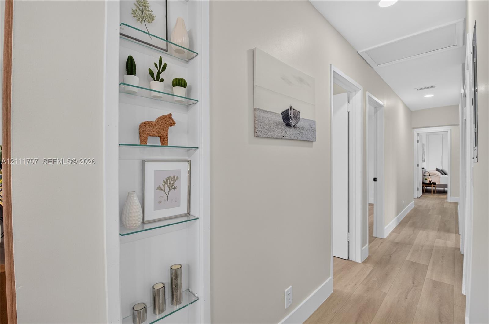 Built-in recessed shelving with glass tiers and wood-finish flooring