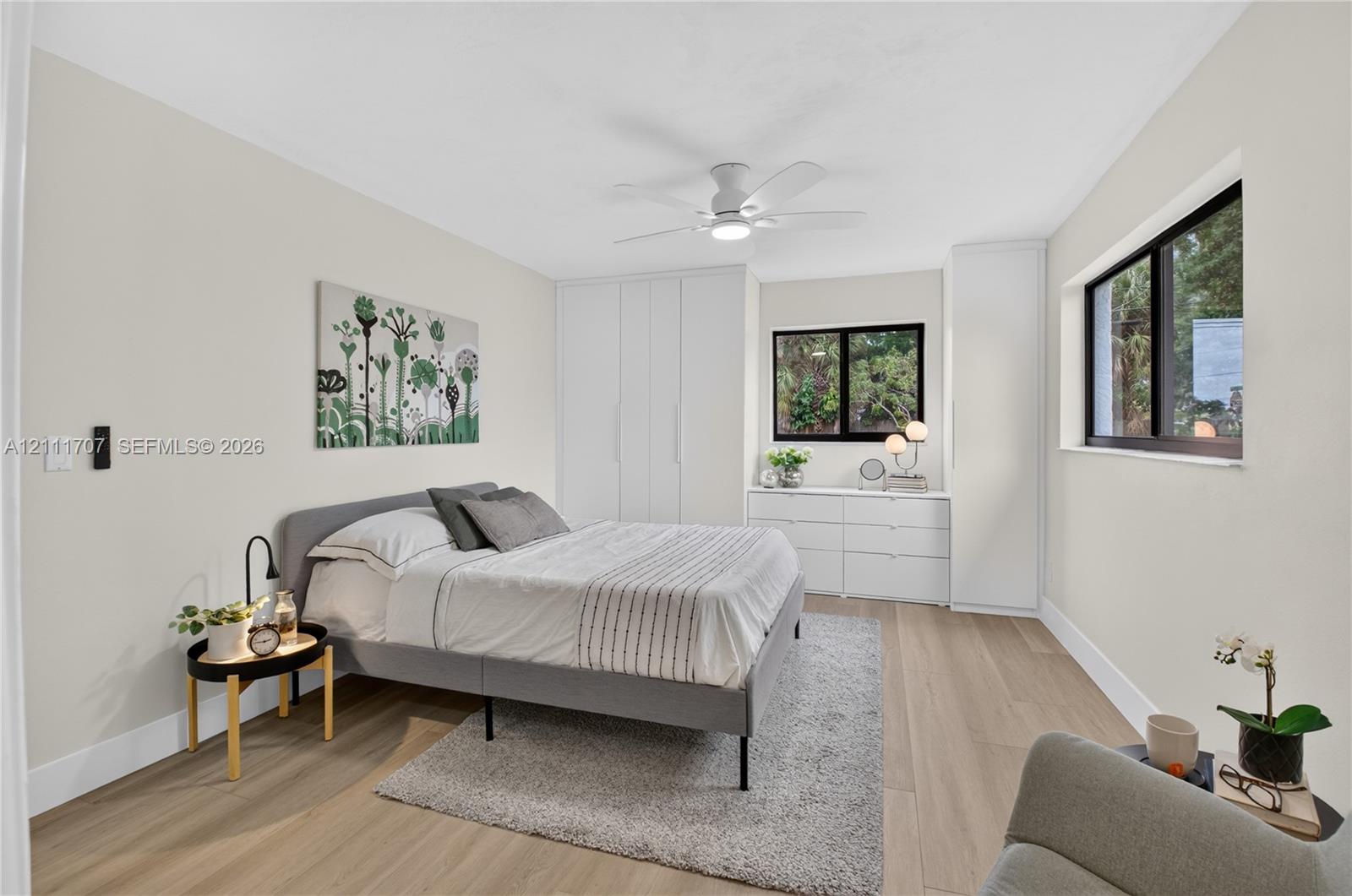 Room featuring wood-finish flooring, built-in floor-to-ceiling cabinetry, dual windows with black frames, and a ceiling-mounted light fixture
