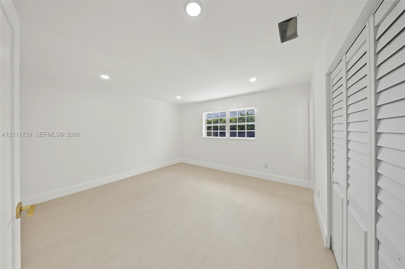 Room featuring neutral walls, light-toned flooring, recessed lighting, and a closet with white louvered doors