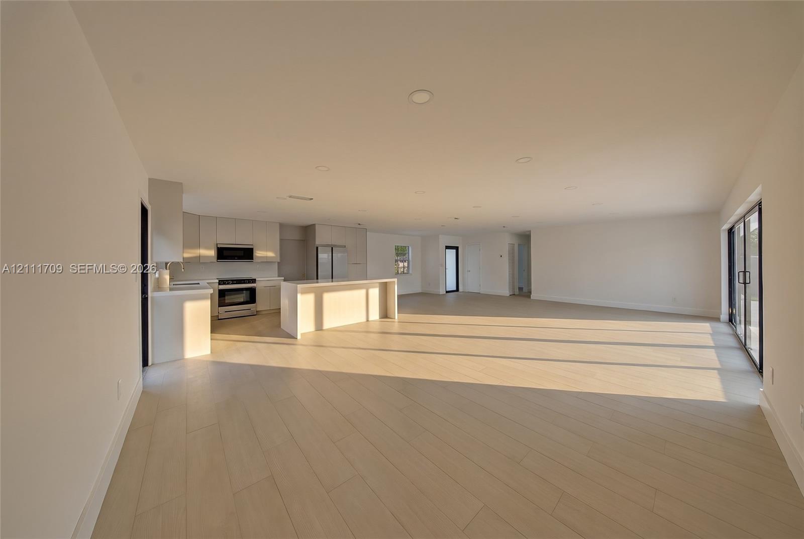 Open concept living space featuring wood-finish flooring, recessed lighting, and sliding glass doors
