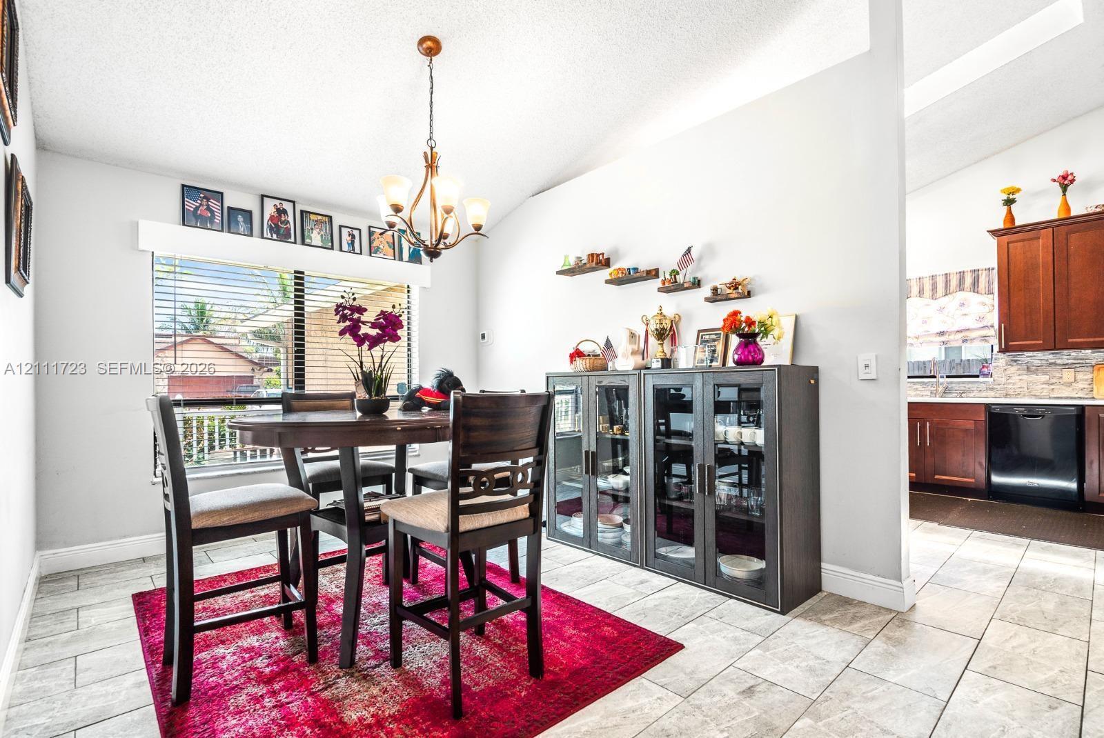 Dining area featuring a vaulted ceiling, multi-light chandelier, and ceramic tile flooring