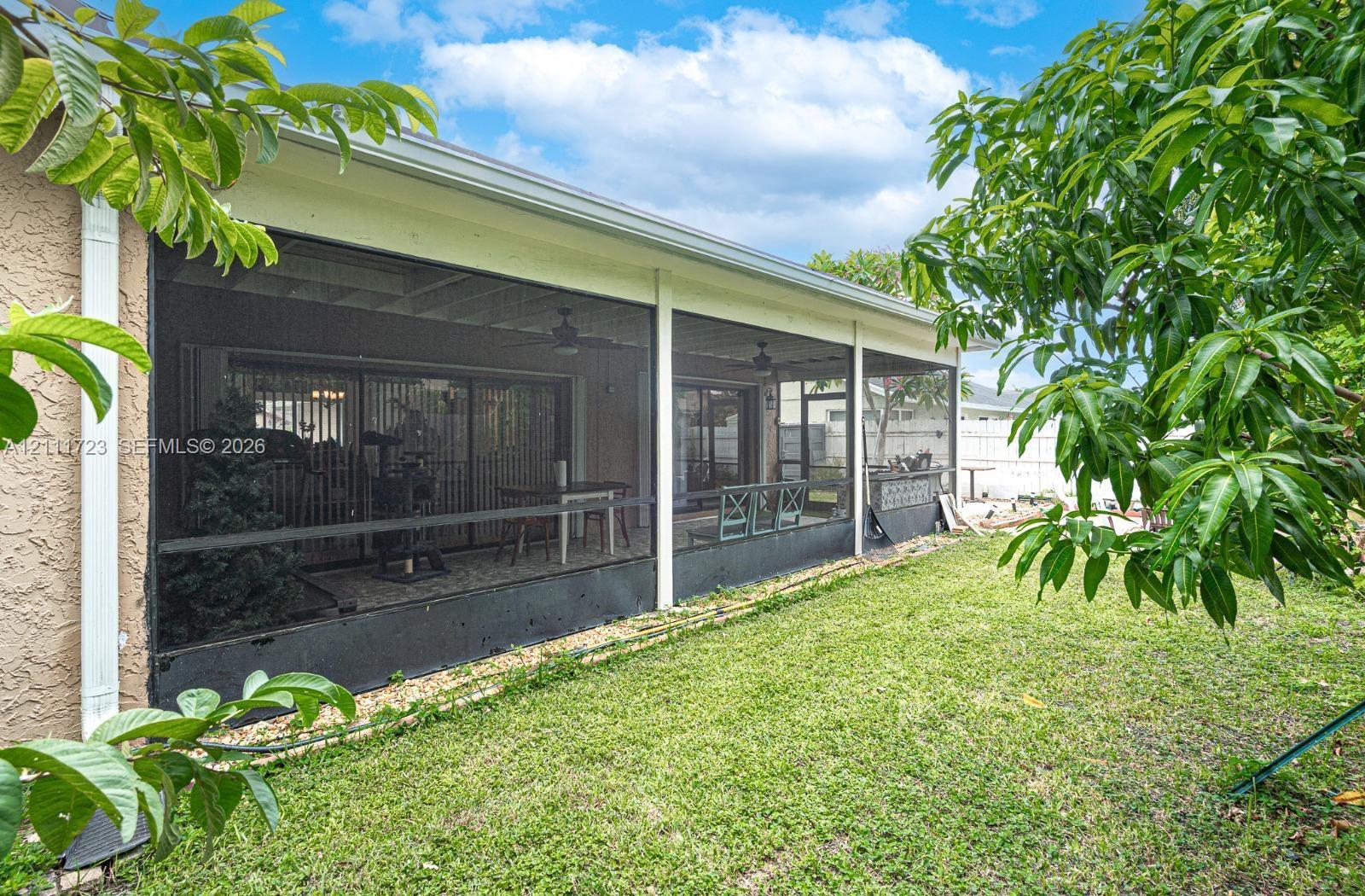 Screen-enclosed patio featuring a solid roof, integrated ceiling fans, and sliding glass door entry