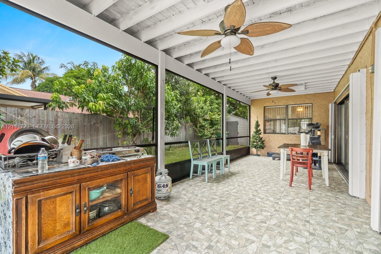 Screened-in patio featuring tiled flooring, dual ceiling fans, and an exterior wall finish