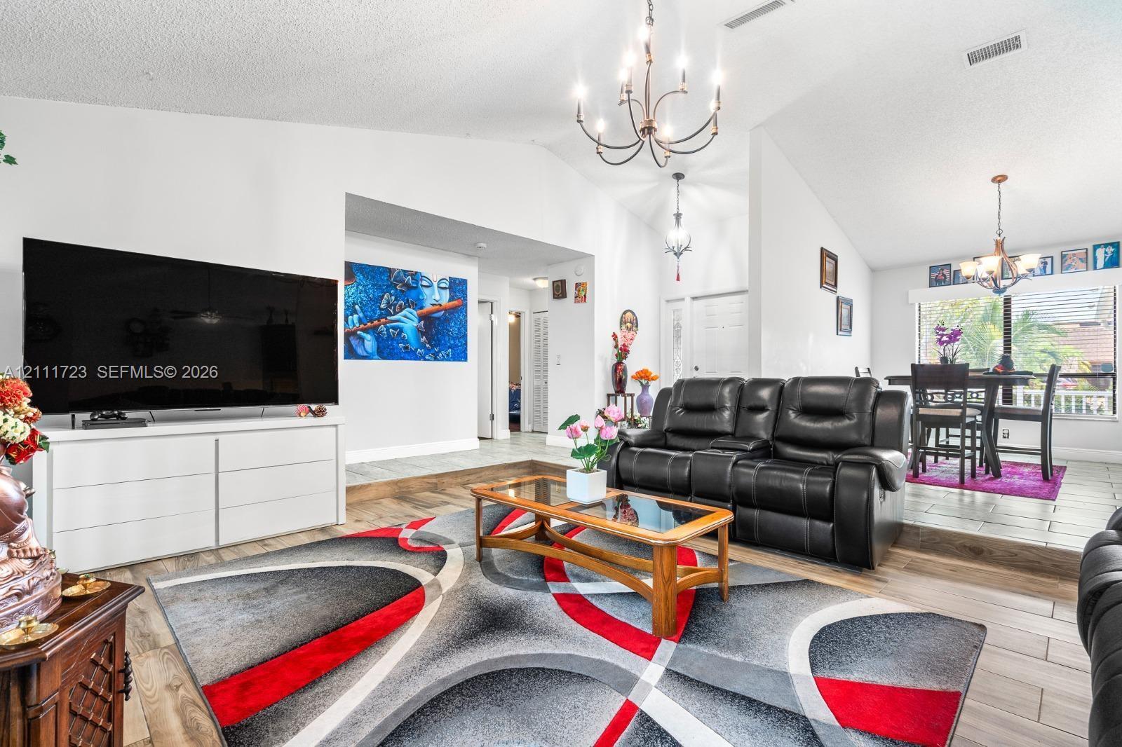 Vaulted ceilings with exposed traditional chandeliers, wood-finish flooring, and a multi-level floor plan